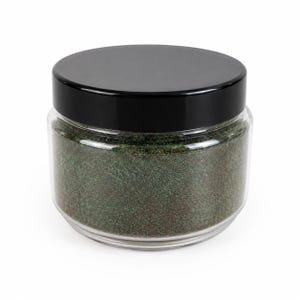 Può includere: Un barattolo cilindrico in vetro trasparente con un coperchio nero liscio a vite. Il barattolo è riempito con una polvere fine verde scuro scintillante, caratterizzata da una qualità metallica e iridescente, visibile attraverso le pareti.