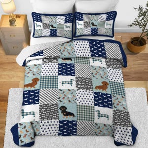 Può includere: Una trapunta patchwork e due federe a tema bassotto. La trapunta e le federe hanno un bordo blu navy e una varietà di motivi, tra cui impronte di zampe, sagome di bassotti e quadri. La tavolozza dei colori comprende blu navy, bianco, grigio e marrone.