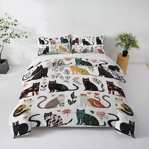 Peut inclure: Une housse de couette blanche et deux taies d'oreiller présentent un motif répété de chats stylisés de différentes couleurs et poses. Les chats sont noirs, orange, gris et sarcelle, avec des accents floraux et de feuilles. L'ensemble de literie est conçu pour un lit.