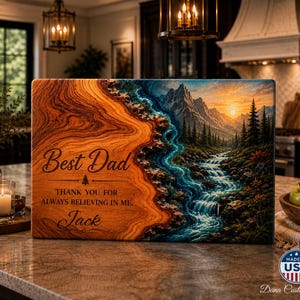 May include: A wooden sign with the words "Best Dad" and a personalized message. The sign features a landscape painting of a river and mountains. The sign is a thoughtful gift for Father's Day or any special occasion.