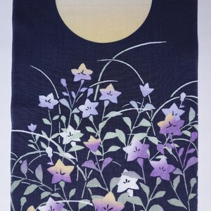 May include: A dark blue fabric with a white moon and a pattern of purple and white flowers on green stems.