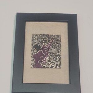 May include: A framed black and white print with a purple silhouette of a person with wings. The background is filled with intricate black and white patterns.