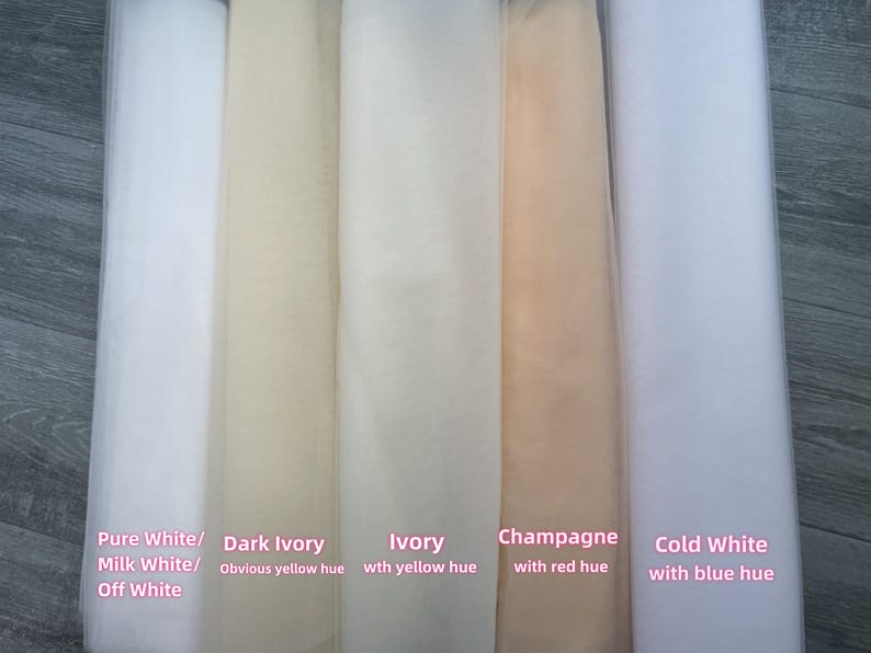 May include: Five vertical rolls of sheer tulle fabric in varying shades. The colours are labelled as Pure White/Milk White/Off White, Dark Ivory with an obvious yellow hue, Ivory with a yellow hue, Champagne with a red hue, and Cold White with a blue hue.