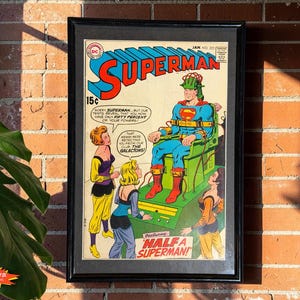 May include: A framed vintage Superman comic book cover, issue number 223, featuring Superman in a green chair with a head device, surrounded by three women. The text reads Superman, Half a Superman, and dialogue bubbles about power levels.