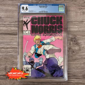 May include: A graded comic book featuring Chuck Norris in a karate pose. The cover is pink and features the title "Chuck Norris Karate Kommandos" with a picture of Chuck Norris kicking a ninja.
