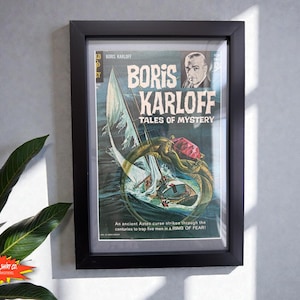 May include: A framed comic book cover titled Boris Karloff Tales of Mystery featuring a sailboat encircled by a large serpent with a red gem on its head. The text reads An ancient Aztec curse strikes through the centuries to trap five men in a RING OF FEAR.