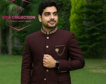 Puede incluir: Un traje granate con botones dorados y un broche decorativo de estrella. El traje tiene un cuello mandarín con bordados dorados. La imagen incluye el texto "ZIYA COLLECTION HANDMADE, HEART-MADE".