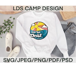 Op de afbeelding: Een wit sweatshirt met een kleurrijk grafisch ontwerp met een zon, wolken en golven. De grafiek zegt "Kijk naar Christus" met de Schriftverwijzing "120:6:36".