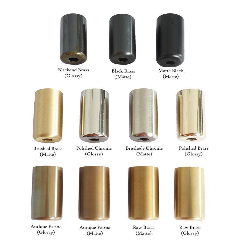 Puede incluir: Una colecci&oacute;n de objetos cil&iacute;ndricos de metal en varios acabados, incluyendo negro, lat&oacute;n y cromo. La imagen muestra muestras etiquetadas como "Blackend Brass", "Black Brass", "Matte Black", "Brushed Brass", "Polished Chrome", "Brushede Chrome", "Polished Brass", "Antique Patina" y "Raw Brass."