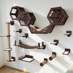 May include: A wooden cat furniture set with multiple platforms, a bridge, and a scratching post. The set includes hexagon-shaped shelves with leaf cutouts, a hammock-style bed, and small square platforms. The pieces are mounted on a white wall.
