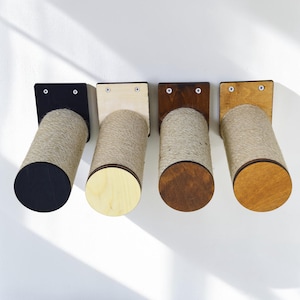 May include: Four wall-mounted cat scratchers. Each scratcher has a wooden base and a cylindrical scratching post wrapped in natural twine. The bases are black, light wood, dark brown, and light brown.