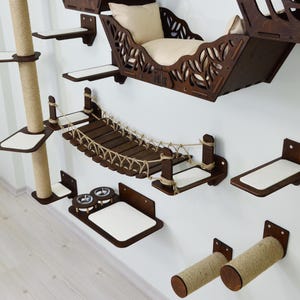 Könnte beinhalten: Eine Wand-Katzenmöbel-Set aus dunkelbraunem Holz. Es enthält ein Katzenbett, Regale, eine Seilbrücke und Kratzbäume. Das Set bietet Katzen Kletter- und Ruhebereiche. Die Regale haben ein weißes Kissen.