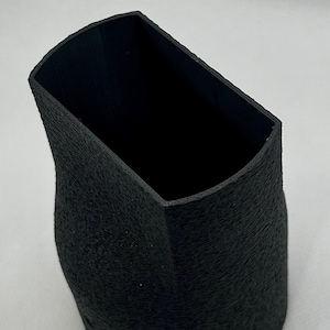 May include: A black, textured, 3D printed, cylindrical vase with a wide opening.