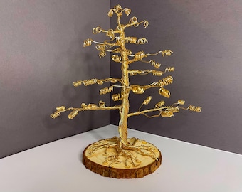 May include: A gold wire tree sculpture with a wooden base. The tree is made of wire that is twisted and curled to resemble branches and leaves. The base is a natural wood slice.