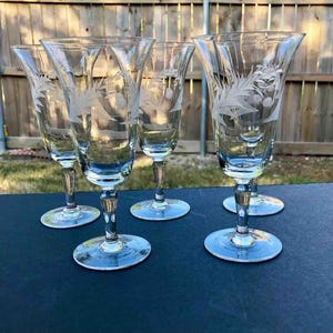 May include: Set of six clear glass wine glasses with etched floral designs. The glasses have a tall, slender stem and a wide bowl.