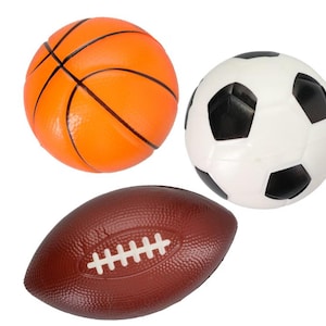 Könnte beinhalten: Drei Sportbälle: ein orangefarbener Basketball mit schwarzen Linien, ein weiß-schwarzer Fußball und ein brauner Football mit weißen Schnürsenkeln. Sie sind vor einem weißen Hintergrund platziert.
