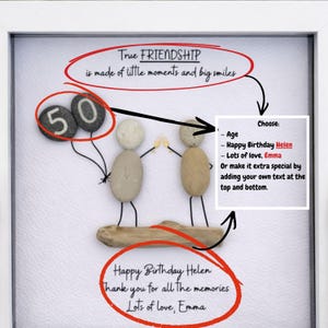 May include: A framed artwork featuring a pebble art design. Two figures made of pebbles are holding hands, with a driftwood base. The artwork includes the text "True FRIENDSHIP" and "Happy Birthday Helen". Two pebbles shaped like balloons display the number "50".