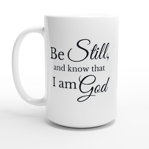Pode incluir: Caneca de cerâmica branca com uma alça curva. A caneca apresenta o texto "Be Still, and know that I am God" em preto. Ideal para bebidas quentes.
