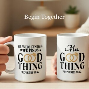 May include: Two white ceramic mugs with black text and gold ring graphics. One mug reads "He Who Finds a Wife Finds a Good Thing Proverbs 18:22." The other mug reads "Mrs. Good Thing Proverbs 18:22." The phrase "Begin Together" is above the mugs.