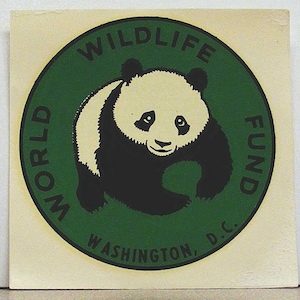 May include: A square sticker featuring a circular green emblem with a black border. Inside the circle is a black and white illustration of a giant panda. The text "WORLD WILDLIFE FUND" and "WASHINGTON, D.C." is printed in black along the border.