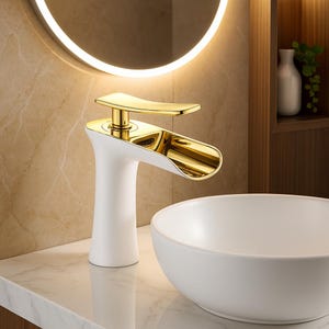 Può includere: Un moderno rubinetto da bagno con base bianca e beccuccio e maniglia dorati. Il rubinetto è posizionato sopra un lavabo rotondo bianco. Lo sfondo include uno specchio circolare illuminato e un piano di lavoro in marmo.