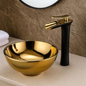 Può includere: Un lavabo dorato a forma di ciotola con un rubinetto dorato abbinato. Il rubinetto ha una base nera e un beccuccio curvo. Il lavabo e il rubinetto sono appoggiati a una parete dai toni neutri.