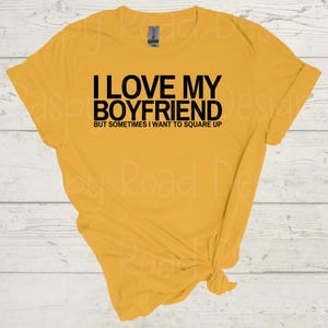 May include: A yellow t-shirt with black text that reads "I love my boyfriend but sometimes I want to square up."
