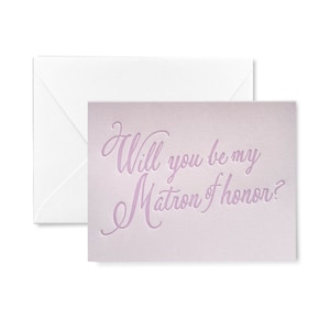 May include: A light pink card with the text "Will you be my Matron of honor?" in a cursive font.