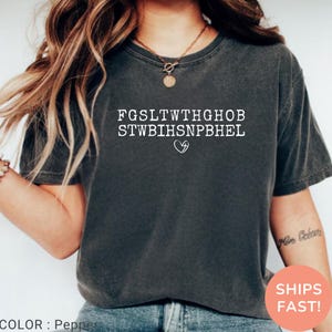 Pu&ograve; includere: T-shirt color pepe con testo bianco e simbolo a cuore. Il testo &egrave; una serie di lettere maiuscole disposte su due righe. La maglietta ha maniche corte e girocollo. Il colore &egrave; descritto come pepe.