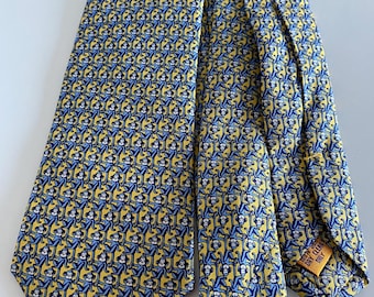 May include: A yellow tie with a repeating pattern of blue monkeys. The tie has a classic shape and is made of a smooth fabric. The tag reads "Dry Clean Only".