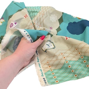 May include: A piece of fabric with a whimsical design featuring flowers, clocks, and geometric patterns in shades of teal, beige, and brown. The fabric has the text "meller ruby star spring 2012" printed along the edge.