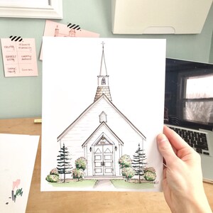 May include: A hand-drawn illustration of a white church with a steeple and a cross on top. The church has a brown roof and a brown door with a stained glass window. There are green bushes and trees around the church.