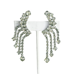 May include: A pair of silver tone dangle earrings with cascading rows of clear rhinestones.