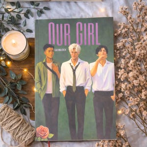 Può includere: Copertina di un libro con il titolo "OUR GIRL" in lettere viola. La copertina presenta tre giovani uomini in vari abiti su uno sfondo verde. È visibile anche il nome dell'autore, GEOBLOCK. Una rosa e un segnalibro rosso sono in basso.