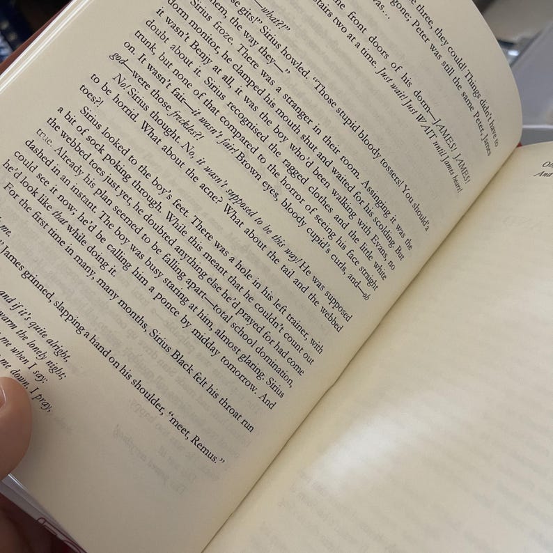 May include: Open book with text on the pages. The text is in black font on off-white paper. The book is open to a page with a paragraph about a boy and his feet. The book is on a dark surface.