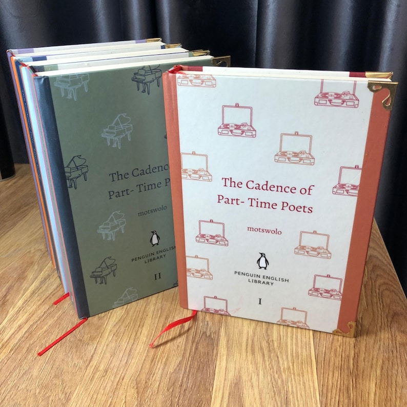 May include: Two hardcover books titled "The Cadence of Part-Time Poets" with decorative illustrations. One book is green with piano graphics, the other is orange with suitcase graphics. Both feature the Penguin English Library logo and red ribbon bookmarks.