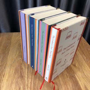 May include: A collection of hardcover books titled "The Cadence of Part-Time Poets." The books have colorful spines in shades of purple, blue, green, and orange. Each book has a red ribbon bookmark and gold corner protectors. The cover of the first book has a pattern of briefcases.