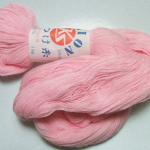 May include: A skein of pale pink cotton yarn with a label that reads "No. 11 Cotton 100% 18g 2570"