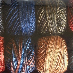 May include: A collection of colorful yarn balls in various shades, including black, blue, red, and gold. The yarn appears to be tightly wound, with visible strands creating a textured surface. The balls are arranged in rows, showcasing the variety of colors.