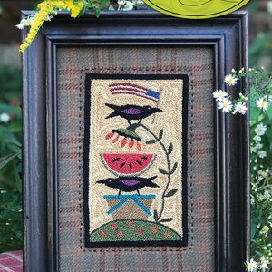 May include: A framed punch needle embroidery design titled "Family Picnic" featuring three black birds perched on a watermelon, a picnic basket, and a green hill. The design is framed in a black frame with a plaid mat. The image includes the text "719 - Family Picnic" and "7 1/4" x 4 1/4" Punchneedle Embroidery".