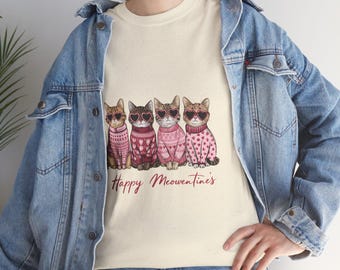 May include: A white t-shirt with a graphic of four cats wearing pink sweaters and heart-shaped sunglasses. The text "Happy Meowentines" is printed below the cats.