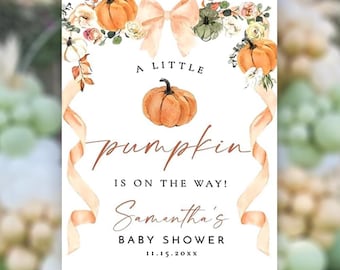 May include: A baby shower sign featuring watercolor pumpkins, floral accents, and a peach bow. The text reads "A Little Pumpkin Is On The Way!" followed by the name "Samantha's" and "Baby Shower" with a date. The sign is displayed on an easel.