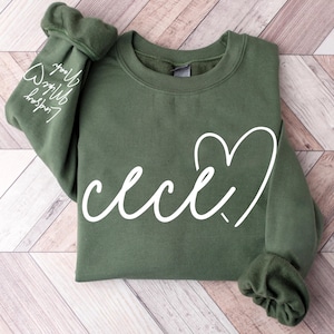 May include: A green sweatshirt with a white heart and the word "cece" written in cursive.