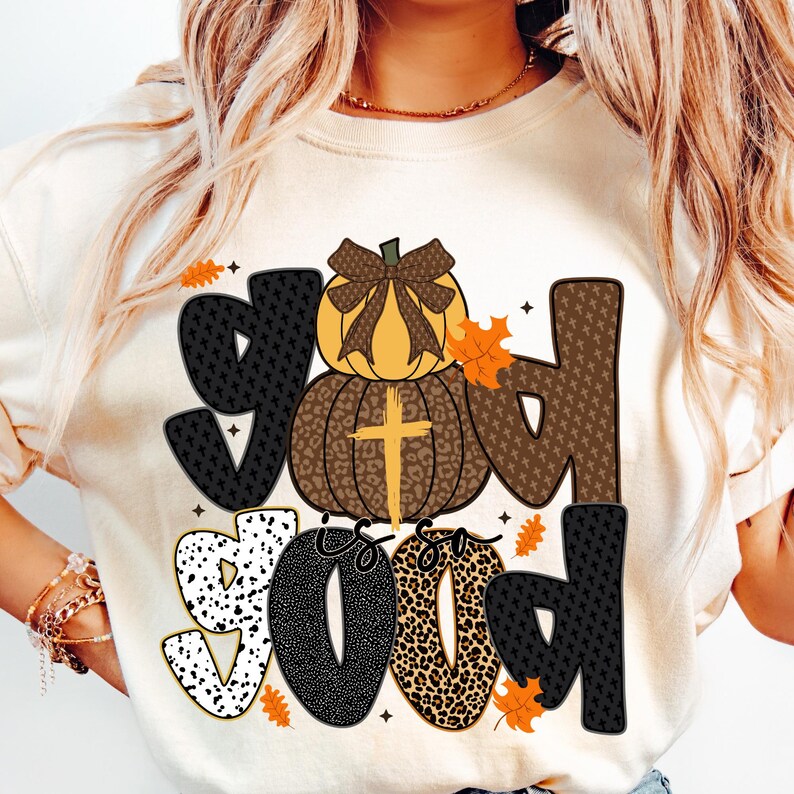 May include: Cream-colored sweatshirt with the phrase "God is so Good" in a mix of patterned fonts. The design includes a pumpkin with a cross and fall leaves, perfect for autumn.