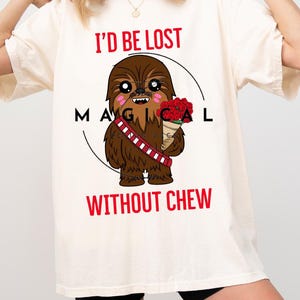 Op de afbeelding: Een wit T-shirt met een cartoon afbeelding van Chewbacca die een bos rode rozen vasthoudt. De tekst "I'd be lost magical without Chew" staat op het shirt gedrukt.
