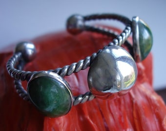 May include: A silver bangle bracelet with a twisted rope design and three green and silver stones.