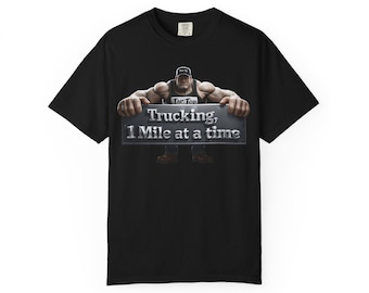 May include: A black short-sleeved t-shirt featuring a graphic of a muscular figure wearing a cap and tank top, holding a rectangular sign with metallic lettering that reads, Trucking, 1 Mile at a time. The shirt has a crew neckline and short sleeves.