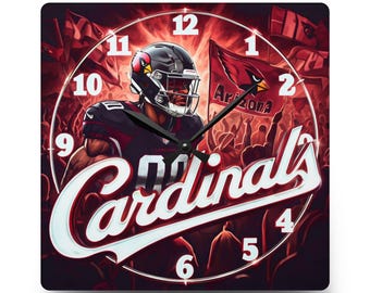 May include: A square wall clock featuring a football player in a black and red uniform with a helmet. The background displays a crowd and a flag with the text Arizona. The word Cardinals is written in large white script across the centre.