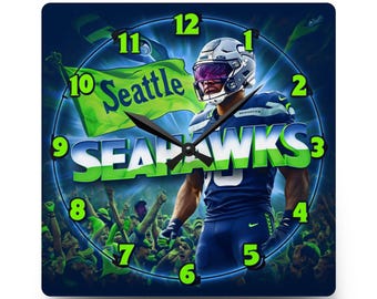 May include: A square wall clock featuring a Seattle Seahawks football player in a dark blue uniform and helmet. The clock face displays the text Seattle Seahawks, bright green numbers from 1 to 12, and black hour, minute, and second hands.