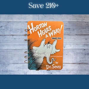 May include: A spiral-bound notebook featuring the cover of Dr. Seuss's "Horton Hears a Who!" The cover is orange with the title in white, a drawing of Horton, and the text "Save 210+". The notebook is on a blue and white wooden surface.